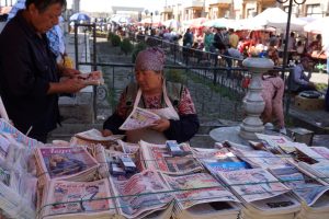 Venditrice di giornali in un'edicola del bazar di Samarcanda, in Uzbekistan, con il mercato tradizionale sullo sfondo.