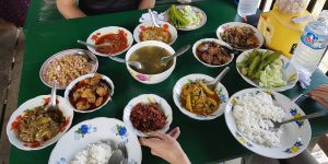 Tavola con piatti della cucina birmana serviti durante un pranzo tradizionale in Myanmar, con riso, curry, verdure e zuppe da condividere.