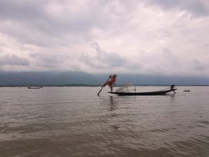 Pescatore Intha che rema con una gamba sulla tradizionale barca del Lago Inle, in Myanmar.