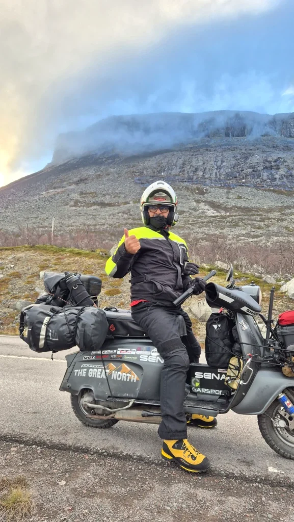 Filippo sulla Lambretta Xena durante The Great North, con montagne rocciose e nuvole basse sullo sfondo.