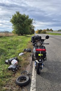 Lambretta ferma sul bordo di una strada nella Repubblica Ceca, con ruota smontata, attrezzi e bagagli appoggiati sull'erba.