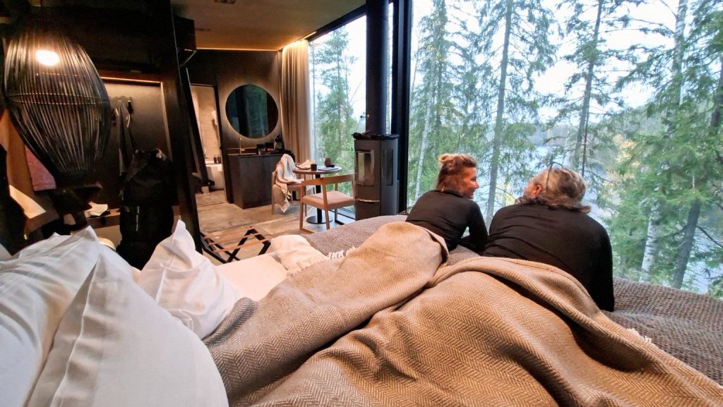 Interno della Kuru Lake Villa con vetrate panoramiche affacciate sul bosco e sul lago in Finlandia.