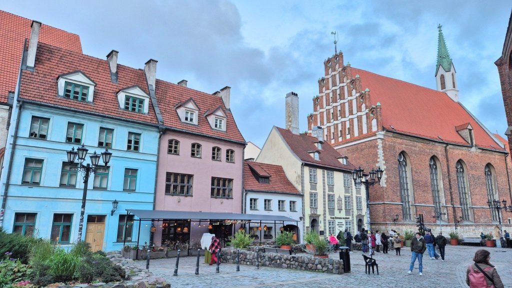 Case colorate e architettura medievale nel centro storico di Riga, con una chiesa gotica sullo sfondo.