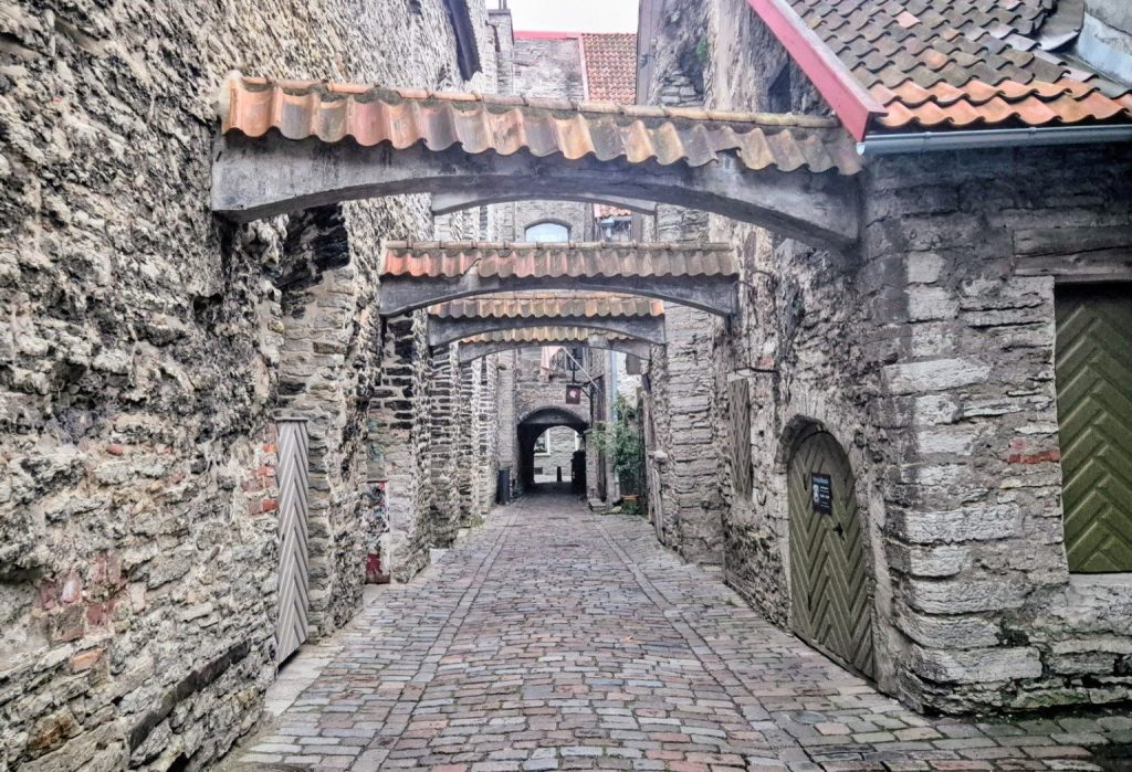 Passaggio di Santa Caterina a Tallinn, vicolo medievale acciottolato con archi in pietra e antichi edifici nel centro storico dell'Estonia.