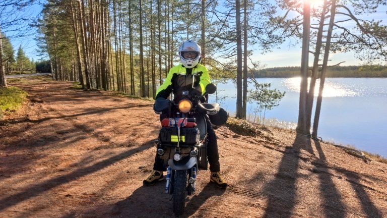 Lambretta Xena lungo un lago circondato da foreste di pini nella regione dei laghi in Finlandia.
